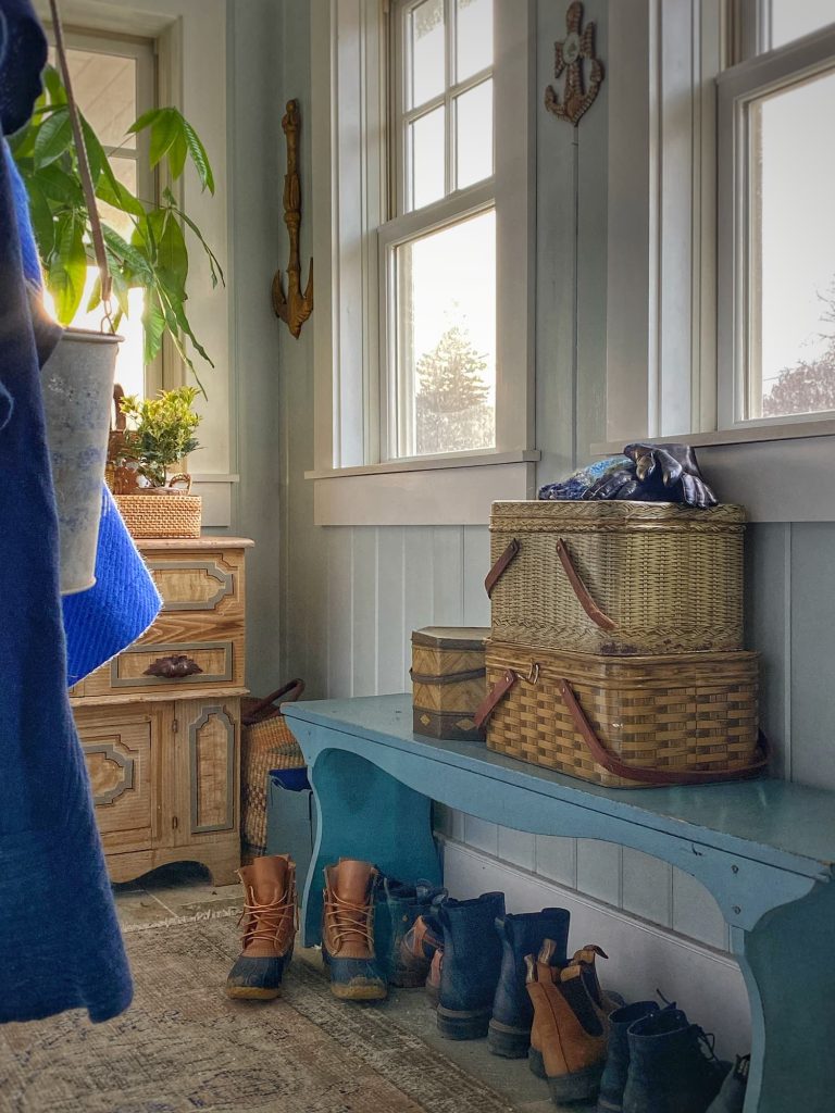 Blue bench with vintage picnic tins in entryway