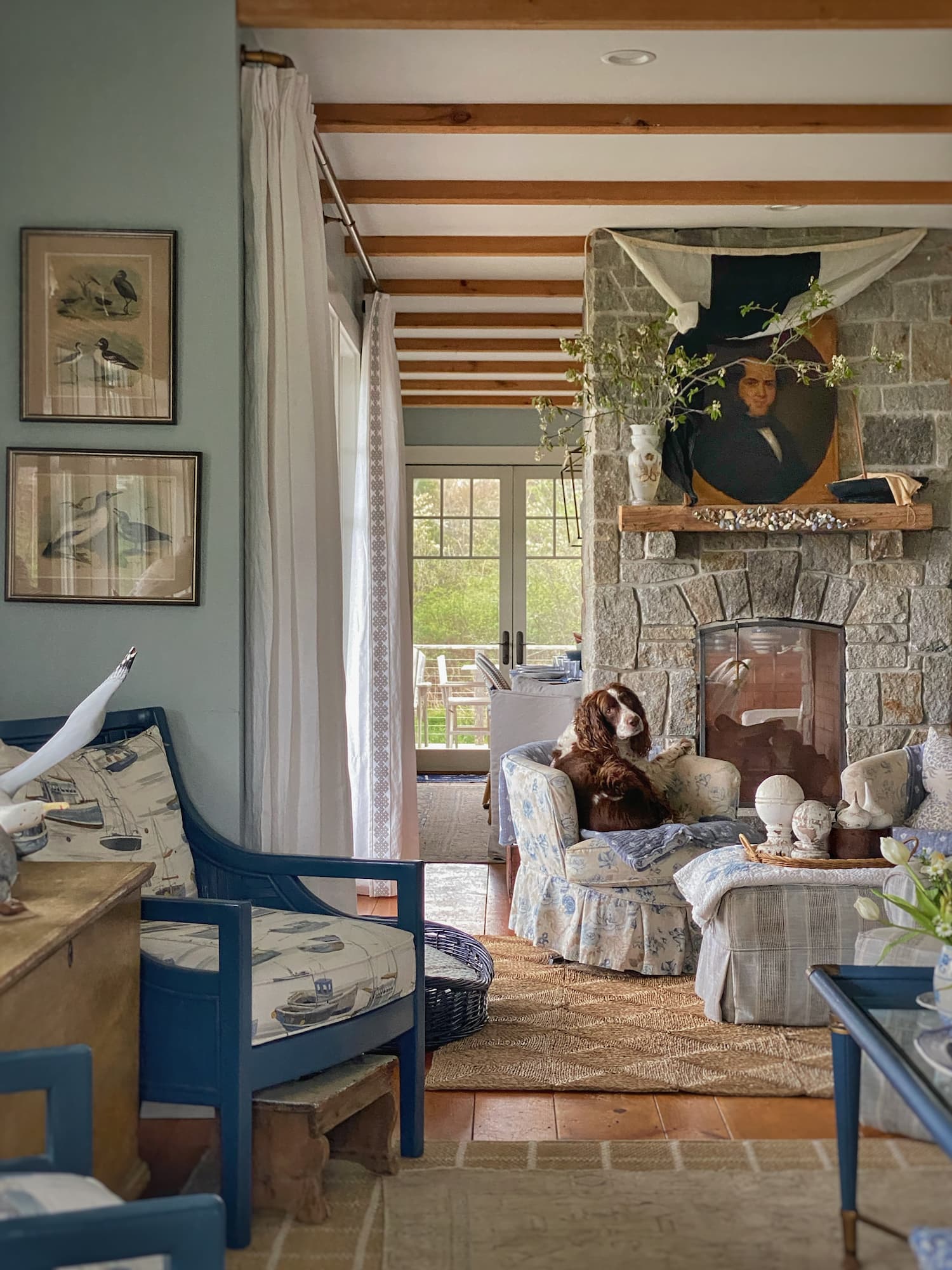 Coastal Maine living room with stone fireplace, antique portrait, and slipcovered furniture.